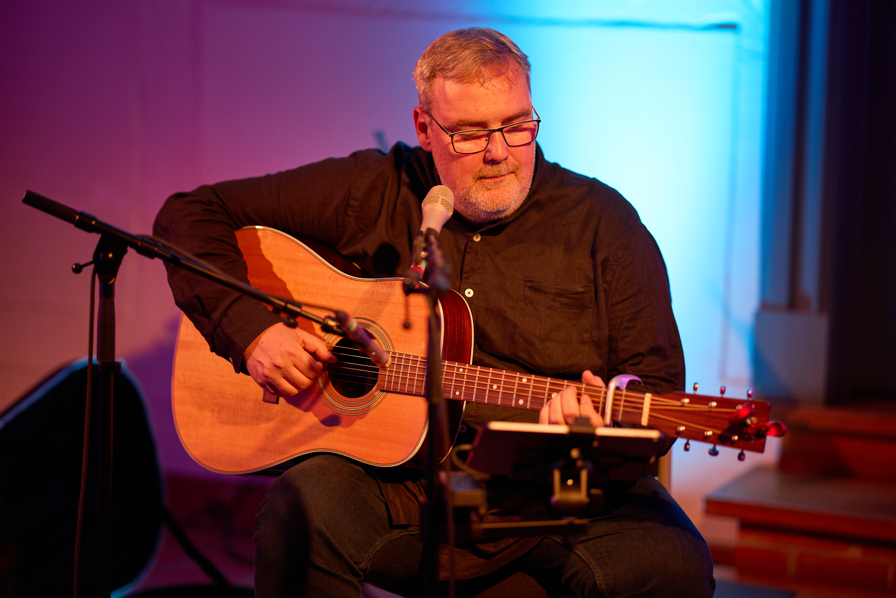 Mann mit Gitarre singt in in Mikrophon