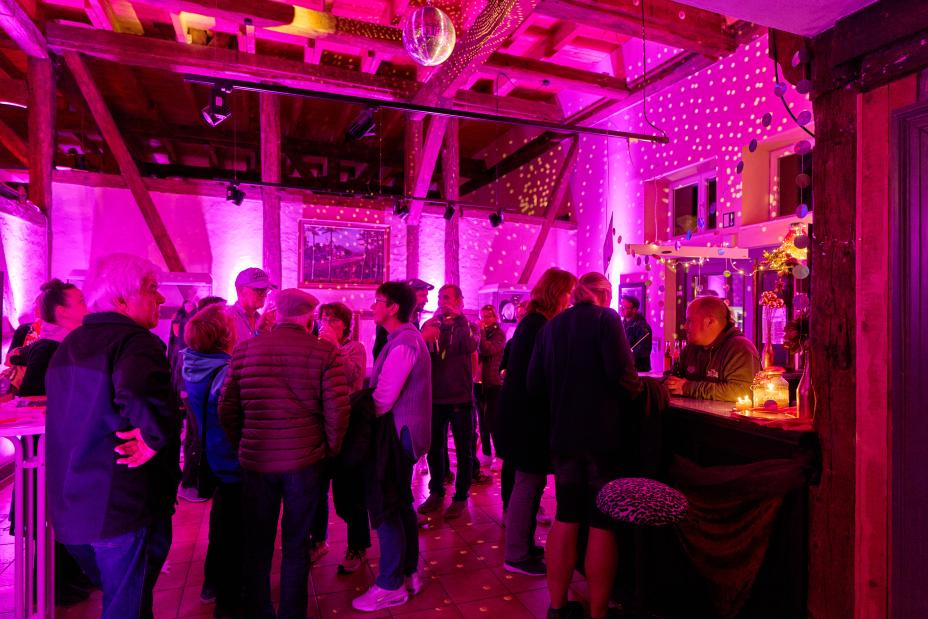 © Oliver Borchert Menschen stehen an der Bar im Museum, der Raum ist lila beleuchtet