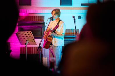 Sänger mit Gitarre sing in ein Mikrofon