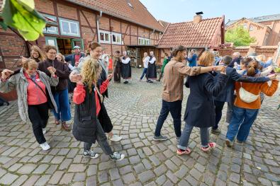 die Teilnehmenden üben einen historischen Rundtanz auf dem Museumshof