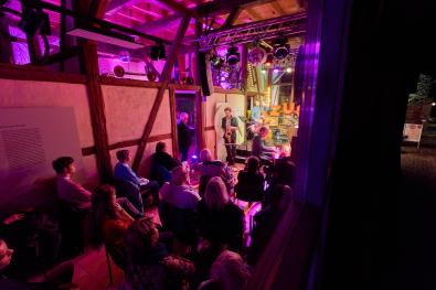 Ein Blick durchs Fenster in die Museumsanlage, bei Nacht, mit einem beleuchteten Konzert