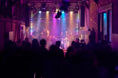 eine Band musiziert auf einer bunt beleuchteten Bühne