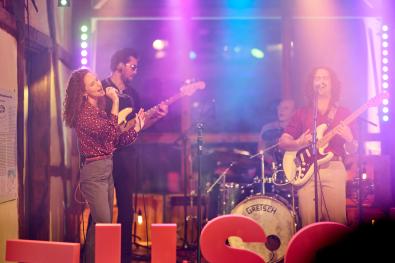 eine Band musiziert auf einer bunt beleuchteten Bühne