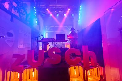 Ein DJ steht auf einer bunt beleuchteten Bühne