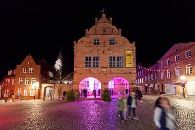 Menschen laufen über den Marktplatz von Gadebusch bei Nacht