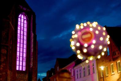 Leuchtendes Kirchenfenster, mit Zusch-Ballon im Hintergrund